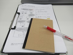 漫画のラフとメモ帳、ペンが机の上にある写真